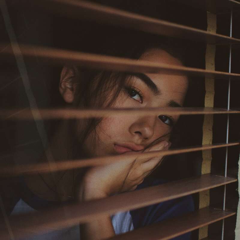 Depressed woman looking out of a window